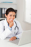 Beautiful female doctor working with her laptop while posing