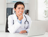 Attractive female doctor working with her laptop while posing