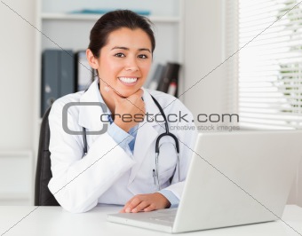 Attractive female doctor working with her laptop while posing