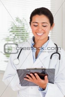 Beautiful female doctor with a stethoscope writing on a notebook