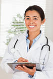 Attractive female doctor with a stethoscope writing on a notebook