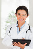 Gorgeous female doctor with a stethoscope writing on a notebook 