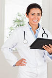 Good looking female doctor with a stethoscope holding a notebook