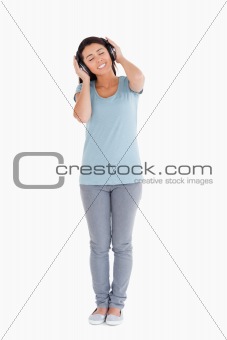 Good looking woman using her headphones while standing