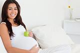 Beautiful pregnant woman holding an apple on her belly 