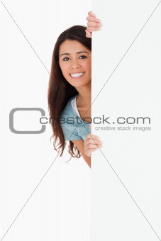 Good looking woman hiding behind a board