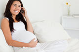 Gorgeous pregnant woman on the phone while lying on a bed