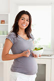 Gorgeous pregnant woman holding a bowl of salad while standing