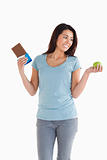 Good looking female holding a chocolate bar and an apple