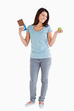 Good looking woman holding a chocolate bar and an apple