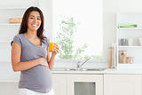 Charming pregnant woman holding a glass of orange juice 