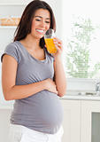 Attractive pregnant woman drinking a glass of orange juice 
