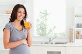 Good looking pregnant woman drinking a glass of orange juice 