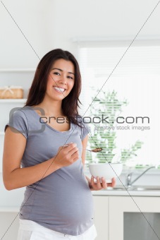 Good looking pregnant woman enjoying a bowl of cereal