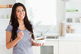 Lovely woman enjoying a bowl of cereals while standing