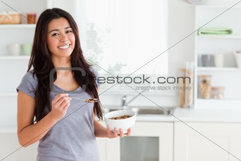 Lovely woman enjoying a bowl of cereals while standing