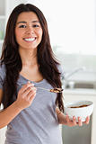 Gorgeous female enjoying a bowl of cereals while standing