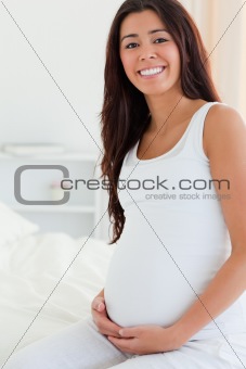 Portrait of a pretty pregnant woman touching her belly 