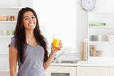 Attractive woman holding a glass of orange juice while standing