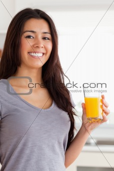 Beautiful woman holding a glass of orange juice while standing