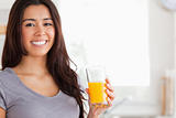 Good looking woman holding a glass of orange juice while standing