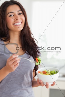 Pretty woman enjoying a bowl of salad while standing