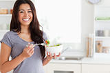 Beautiful woman enjoying a bowl of salad while standing