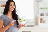 Attractive woman enjoying a bowl of salad while standing