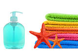 Blue soap bottle, stacked colorful towels and red seastars on a 