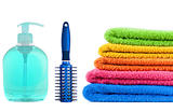 Blue soap bottle, massages comb and stacked colorful towels on a