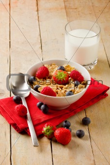 Corn flakes with berries on wooden table