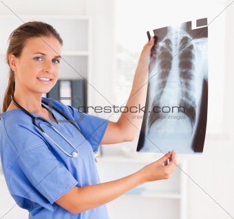 Gorgeous doctor with stethoscope and x-ray looking into camera