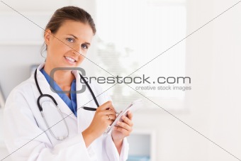 Concentrated doctor writing something down looking into the camera