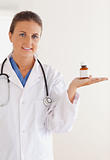 Good looking brunette doctor with stethoscope looking at some pills