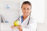 Doctor with stethoscope looking at an apple