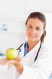 Smiling doctor with stethoscope looking at an apple
