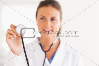 gorgeous brunette doctor showing stethoscope to the camera