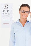 Good looking brunette eye specialist wearing glasses looking into the camera