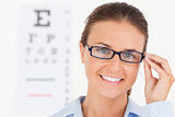 Close up of a good looking brunette eye specialist wearing glasses looking into the camera