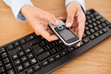 Woman holding mobile phone above keyboard