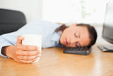 Sleeping businesswoman with coffee in office