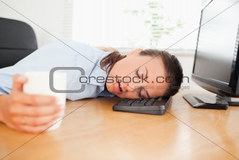 Sleeiping woman in an office holding coffee