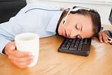 Businesswoman with headset sleeping in office with coffee