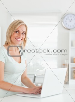 Blonde woman with a laptop looking into the camera