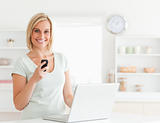 Cute woman with a mobile and a laptop looking into the camera