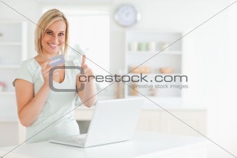 Blonde woman with credit card and notebook holding thumb up 