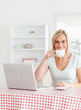 Woman drinking coffee with notebook in front of her