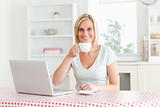 Woman drinking coffee with laptop in front of her 