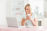 Woman holding coffee with laptop in front of her