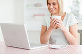 Close up of a woman holding coffee with laptop in front of her